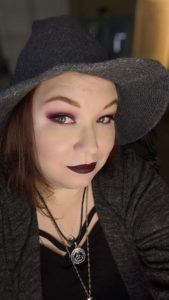 redhead in gray witch hat with makeup and siler necklaces