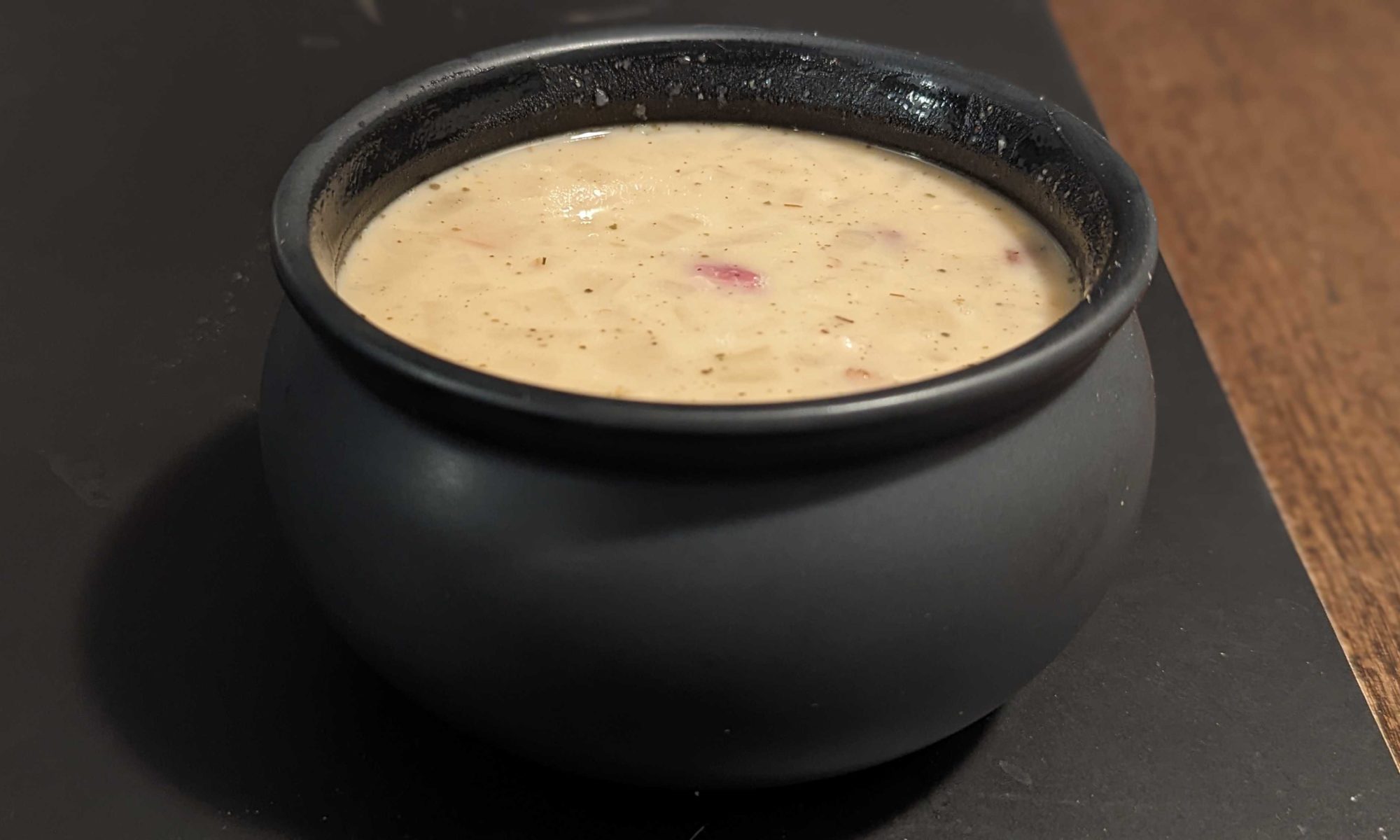a small black cauldron bowl full of navy bean soup
